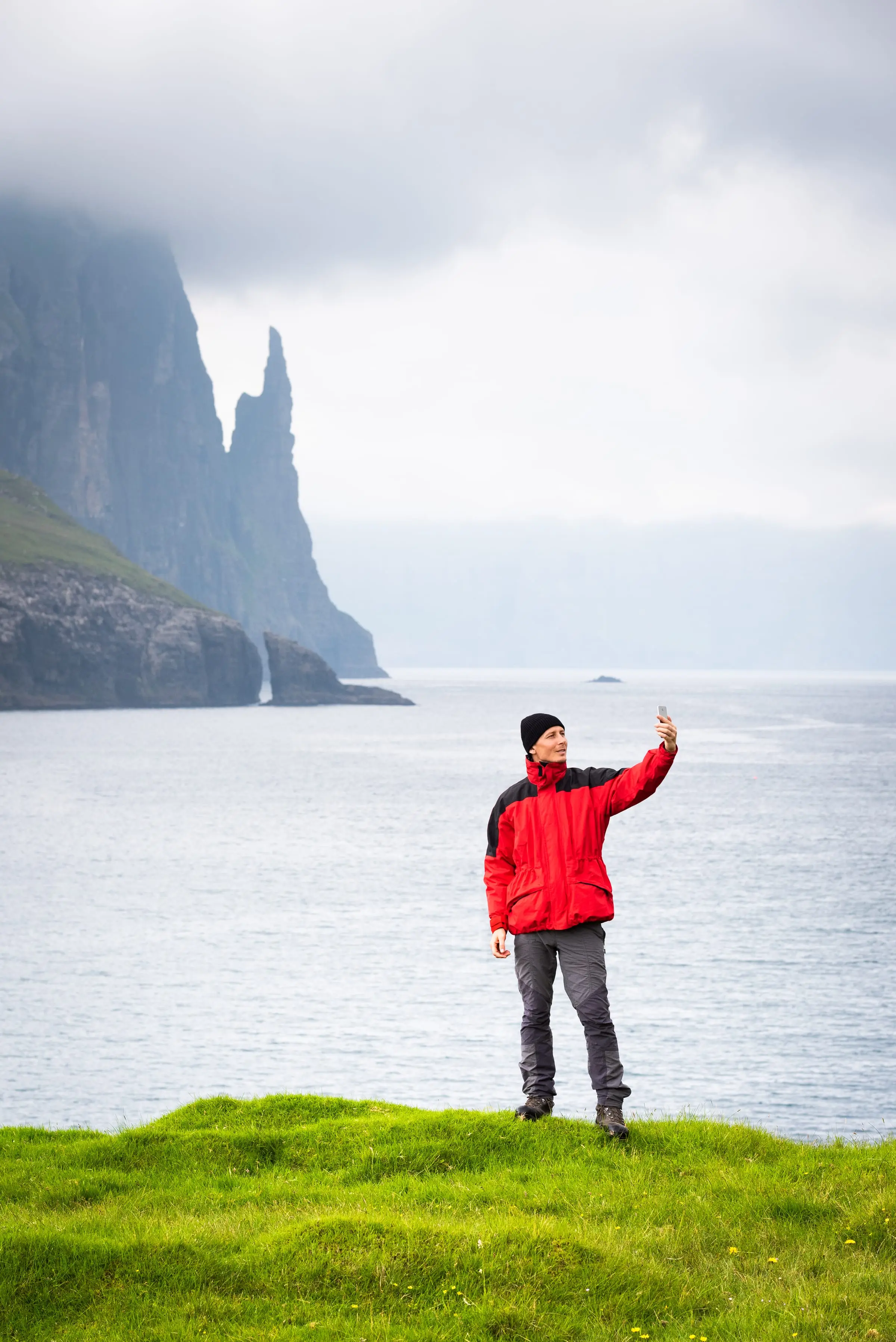A person using a phone in front of a Faroese landscape