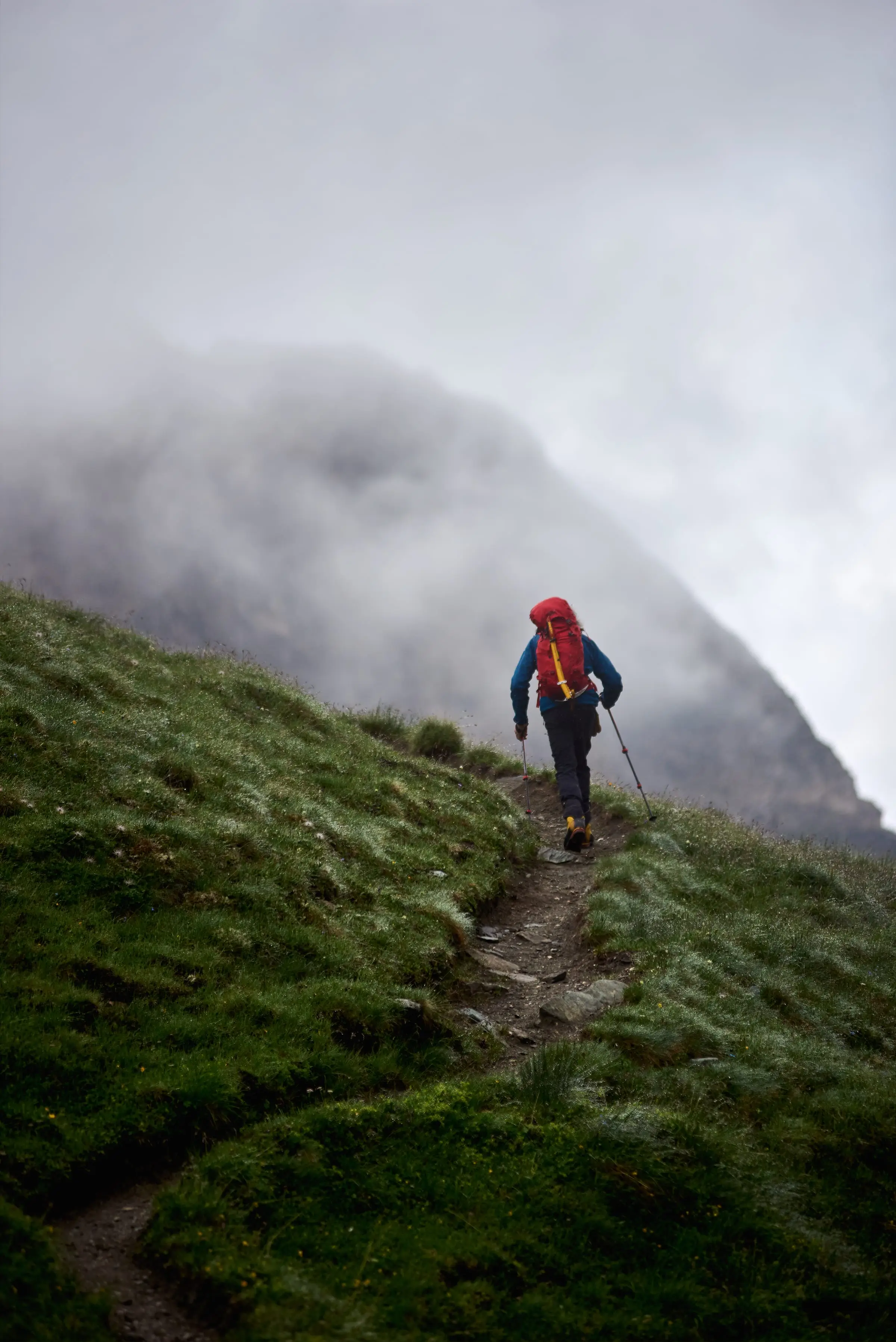 A hiker next to a stone cairn on a trail in the fog