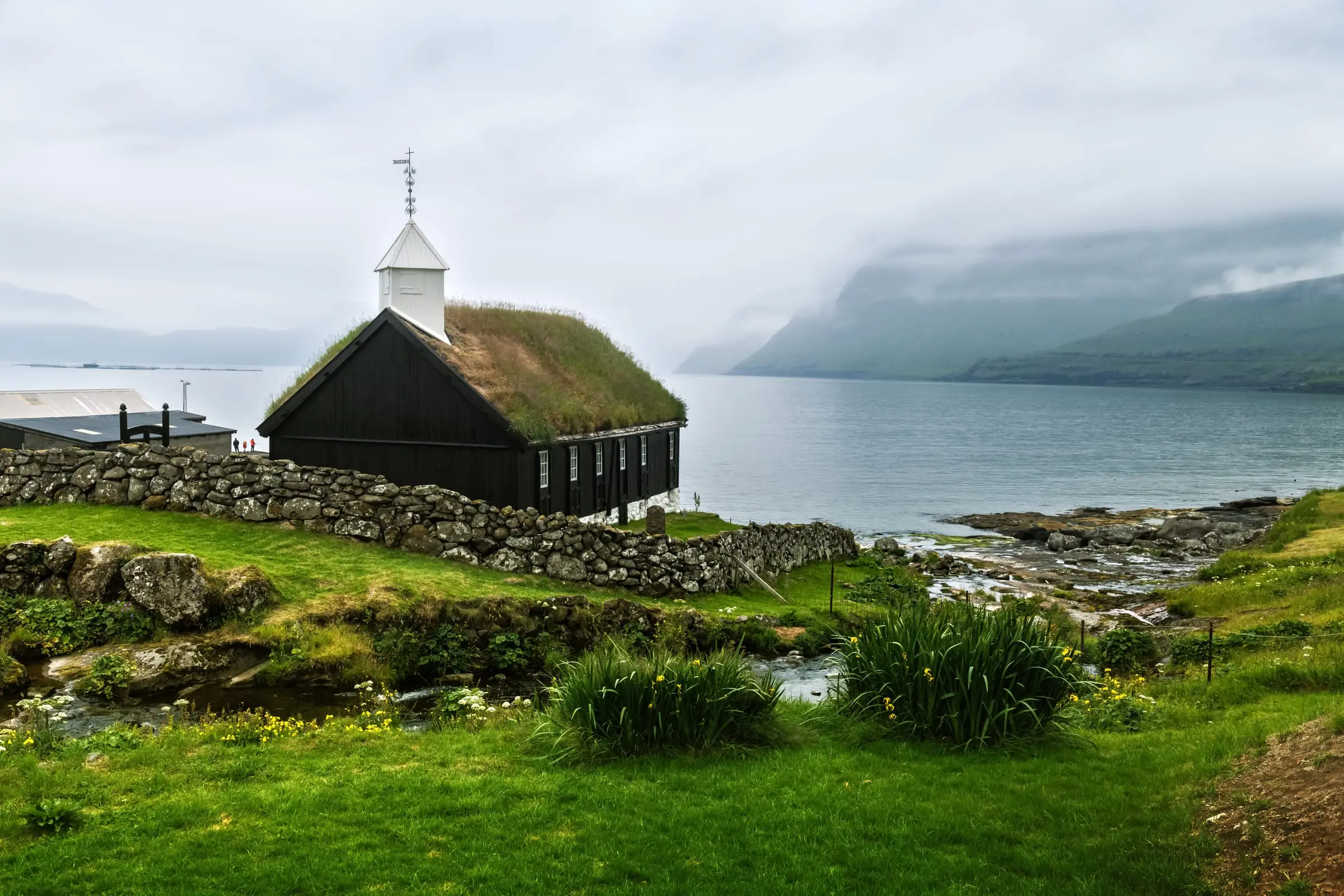 Iglesia blanca de Viðareiði frente al mar y las montañas
